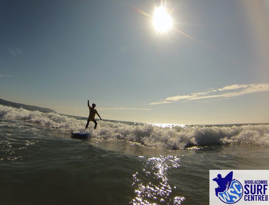 first time surfer up and riding the wave, happy surfer learning to surf at Woolacombe Beach in the school holidays with Woolacombe Surf Centre